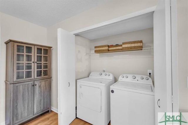 laundry room with laundry area, light wood finished floors, independent washer and dryer, and a textured ceiling
