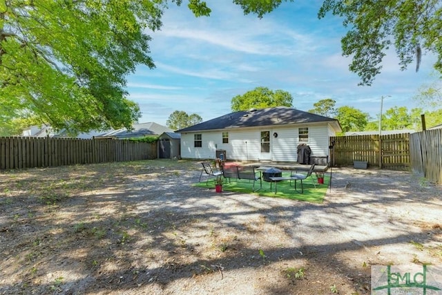 rear view of house with a patio area, a storage shed, a fire pit, an outbuilding, and a fenced backyard