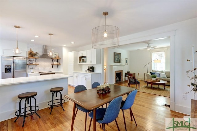 402 E 56th St, Savannah, GA 31405 - dining space with ceiling fan, a brick fireplace, light wood-style floors, and visible vents