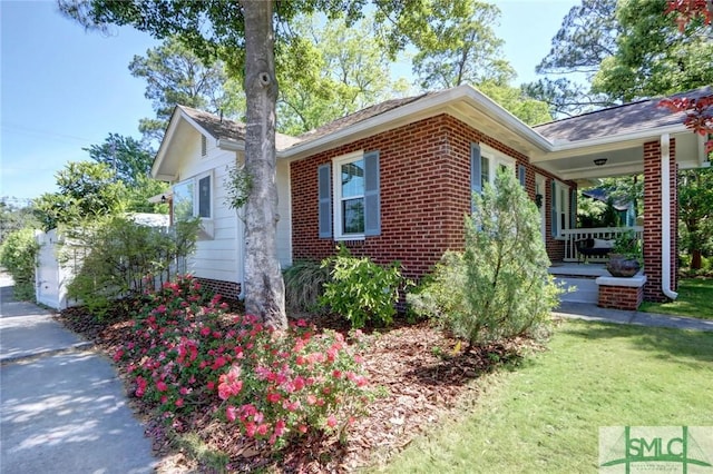 402 E 56th St, Savannah, GA 31405 - view of home's exterior featuring covered porch, brick siding, and a yard