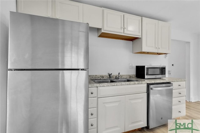 627 W 48th St, Savannah, GA 31405 - kitchen with light stone counters, a sink, light wood-type flooring, white cabinets, and appliances with stainless steel finishes