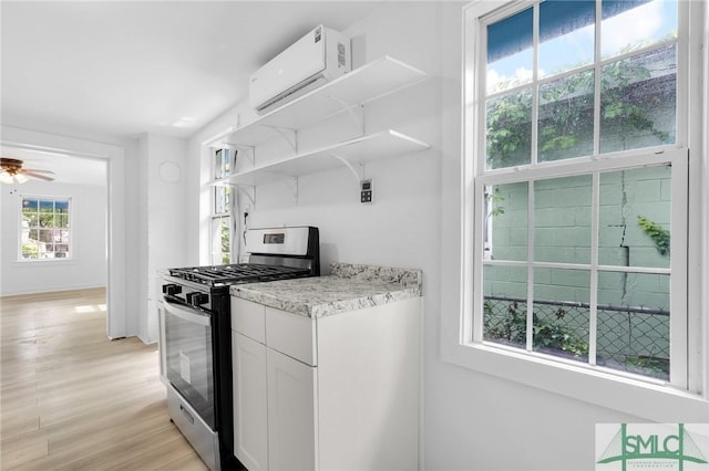 627 W 48th St, Savannah, GA 31405 - kitchen featuring white cabinets, a wall mounted air conditioner, stainless steel gas range oven, open shelves, and light wood-type flooring
