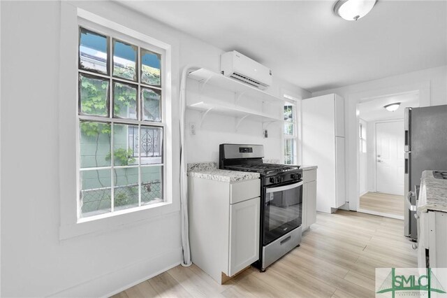 627 W 48th St, Savannah, GA 31405 - kitchen featuring stainless steel appliances, white cabinetry, light wood-style floors, and a wall unit AC
