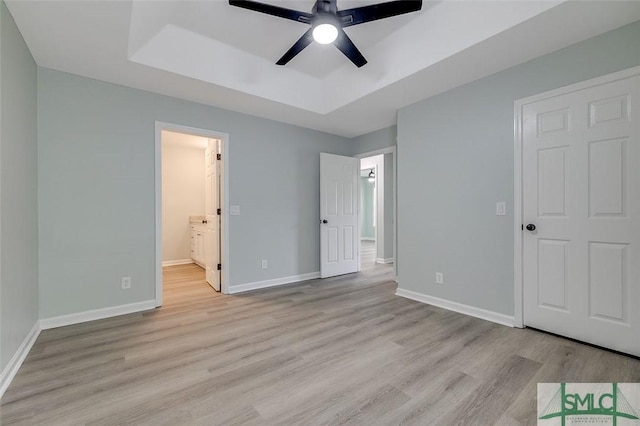 126 Four Oaks Ct, Rincon, GA 31326 - unfurnished bedroom featuring baseboards, a raised ceiling, connected bathroom, and light wood finished floors