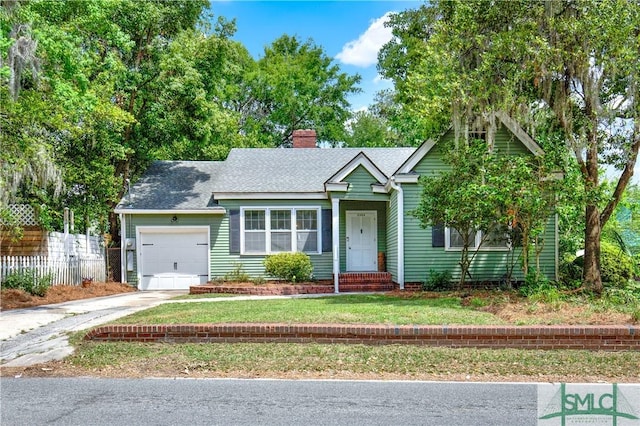 view of front facade featuring a front yard, driveway, a chimney, an attached garage, and fence
