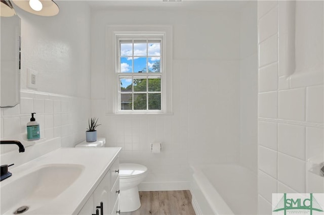 full bathroom with tile walls, wood finished floors, toilet, and vanity