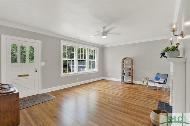 foyer entrance with crown molding, light wood finished floors, a ceiling fan, and baseboards