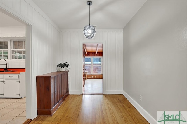 interior space featuring baseboards, light wood finished floors, and a sink