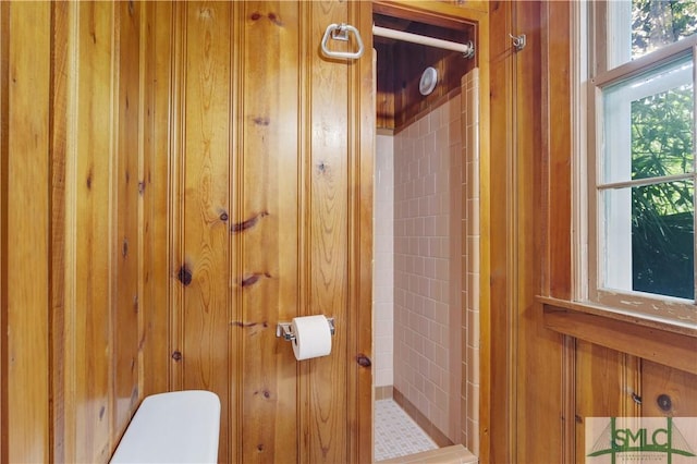 bathroom with wooden walls, toilet, and a stall shower