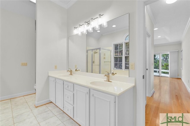 full bathroom featuring a shower stall, crown molding, a sink, double vanity, and baseboards