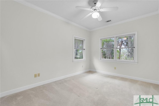 carpeted spare room with baseboards, a ceiling fan, visible vents, and ornamental molding
