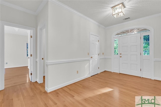 entryway featuring visible vents, light wood finished floors, baseboards, and ornamental molding