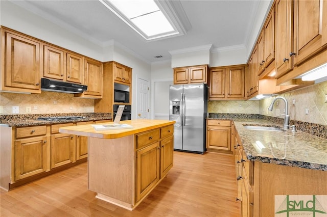 kitchen featuring light wood finished floors, under cabinet range hood, a sink, a center island, and black appliances