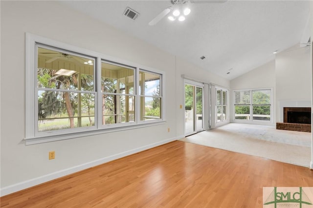 unfurnished living room with wood finished floors, visible vents, a ceiling fan, baseboards, and a fireplace