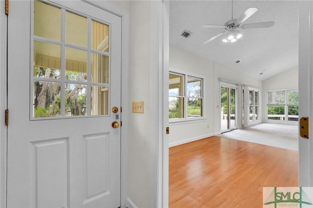 doorway to outside with lofted ceiling, wood finished floors, visible vents, baseboards, and ceiling fan