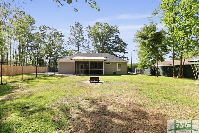 620 W 9th St, Rincon, GA 31326 - rear view of house with a fenced backyard, a sunroom, a yard, and an outdoor fire pit