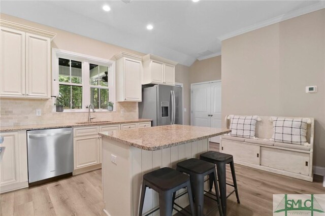 620 W 9th St, Rincon, GA 31326 - kitchen featuring a kitchen breakfast bar, a sink, decorative backsplash, light wood-style floors, and stainless steel appliances