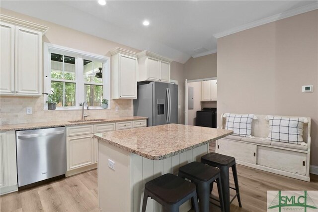 620 W 9th St, Rincon, GA 31326 - kitchen with a sink, decorative backsplash, light wood-style floors, a breakfast bar area, and appliances with stainless steel finishes