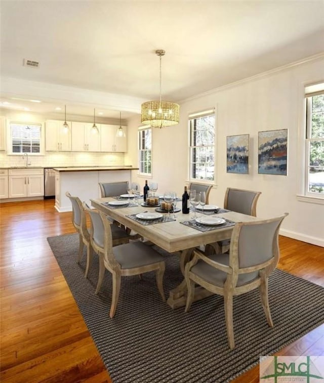 dining room featuring visible vents, baseboards, ornamental molding, wood finished floors, and a notable chandelier