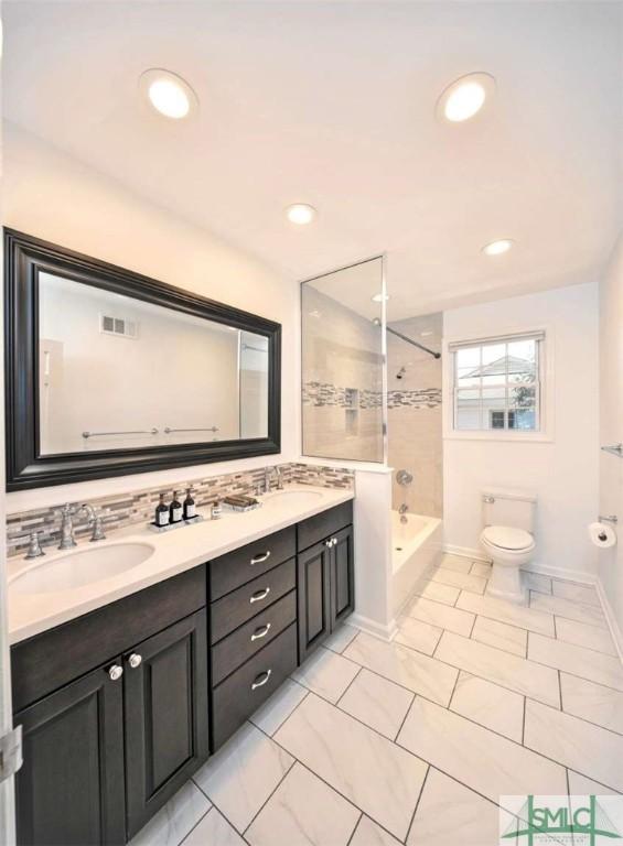 full bath with double vanity, toilet, shower / washtub combination, a sink, and visible vents