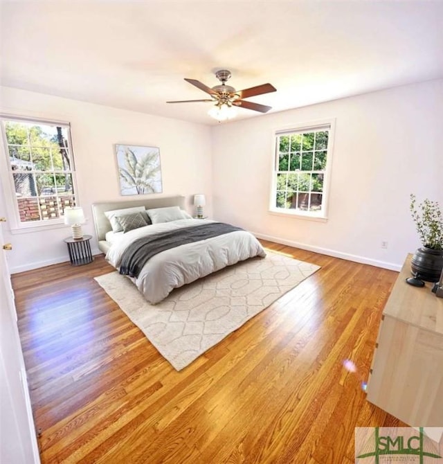 bedroom featuring baseboards, wood finished floors, and ceiling fan