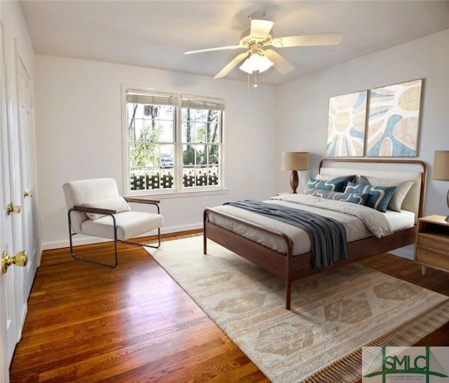 bedroom with a ceiling fan, wood finished floors, and baseboards