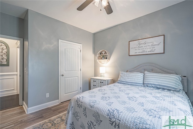 bedroom with ceiling fan, wood finished floors, and baseboards