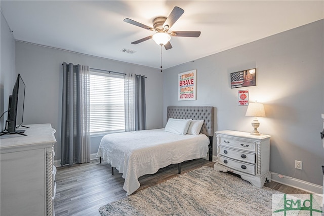 bedroom featuring wood finished floors, ceiling fan, visible vents, and baseboards
