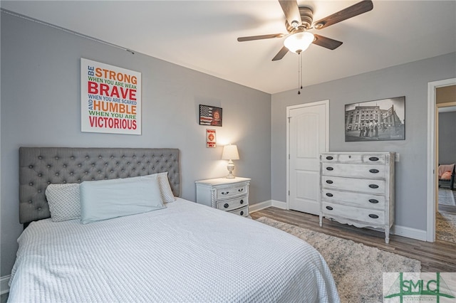 bedroom with baseboards, wood finished floors, and a ceiling fan