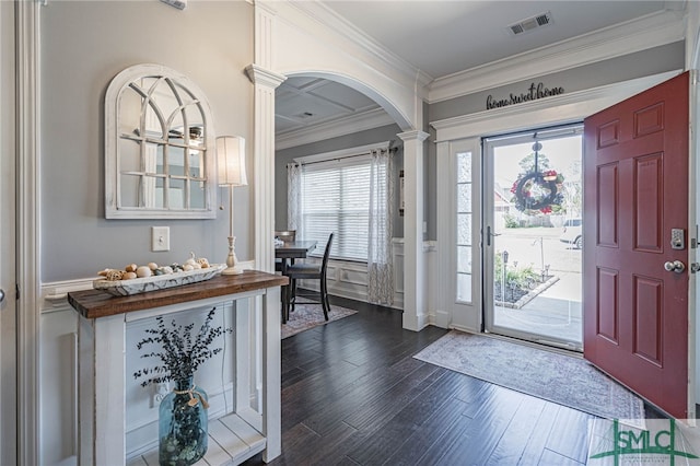 foyer featuring crown molding, visible vents, arched walkways, dark wood finished floors, and decorative columns