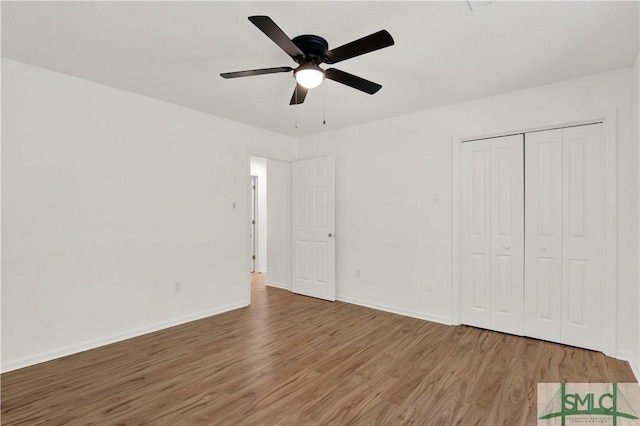 unfurnished bedroom with baseboards, wood finished floors, ceiling fan, and a closet