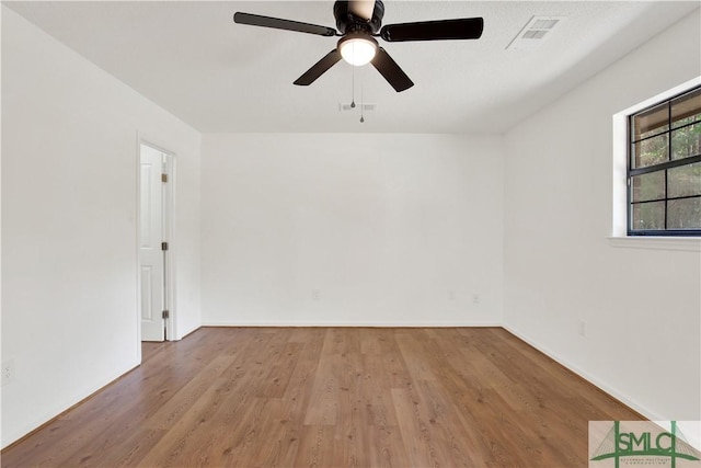 empty room featuring baseboards, visible vents, wood finished floors, and a ceiling fan