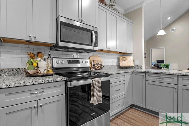 107 Mingledorff Way, Springfield, GA 31329 - kitchen featuring crown molding, light wood-style flooring, appliances with stainless steel finishes, light stone countertops, and backsplash