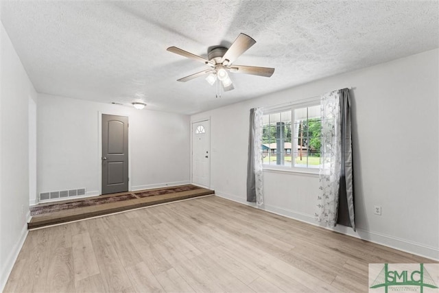 interior space featuring wood finished floors, visible vents, a ceiling fan, and a textured ceiling