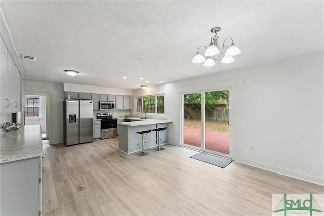 kitchen featuring gray cabinetry, a peninsula, appliances with stainless steel finishes, and light countertops