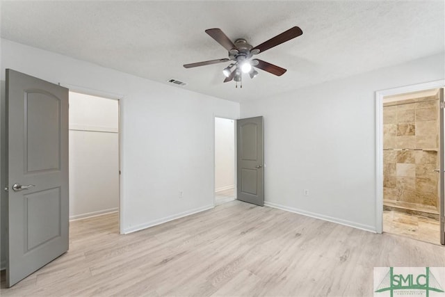 unfurnished bedroom with visible vents, light wood-style floors, a closet, baseboards, and a spacious closet