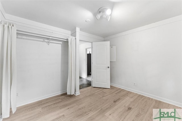 unfurnished bedroom with a closet, light wood finished floors, and baseboards