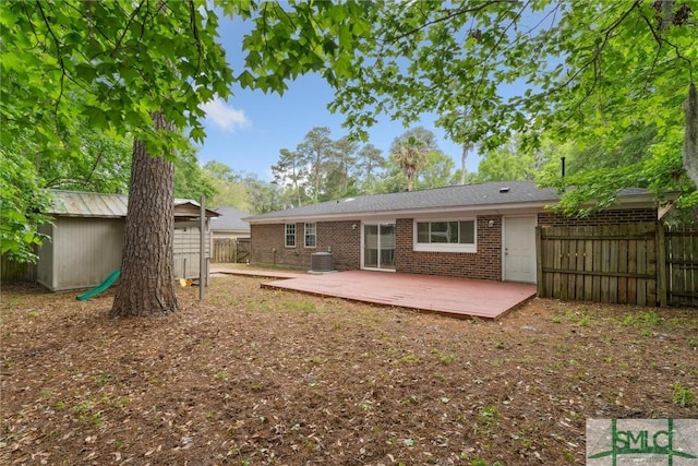 back of house with a storage shed, central AC unit, an outbuilding, and a fenced backyard