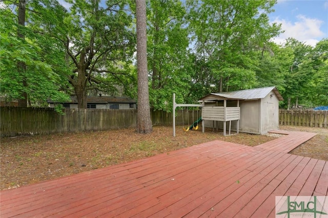 wooden terrace featuring an outbuilding, a shed, a playground, and a fenced backyard