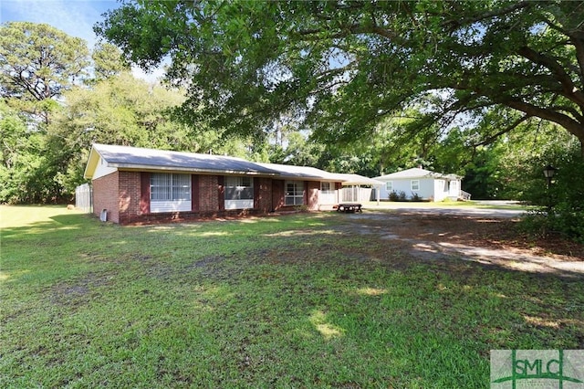 ranch-style home featuring brick siding, driveway, and a front yard