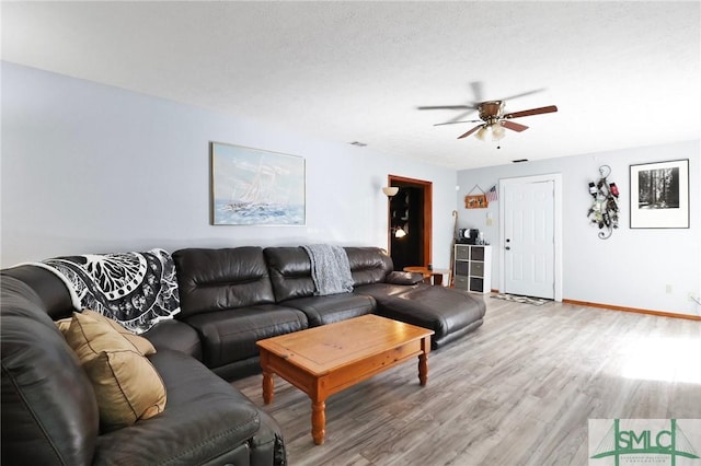 living area with baseboards, light wood finished floors, and ceiling fan