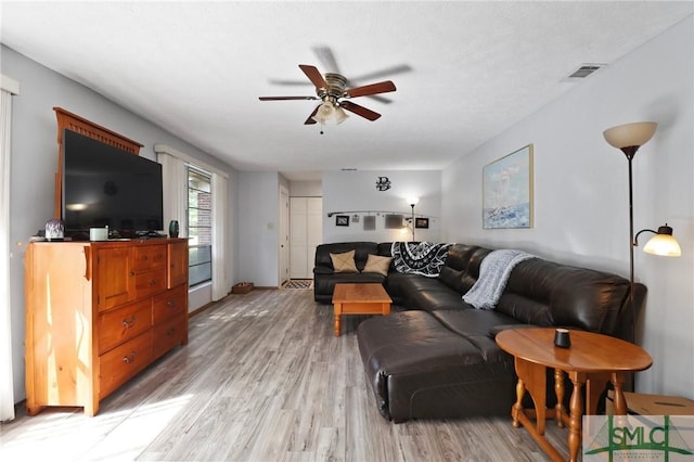living room with a ceiling fan, light wood finished floors, and visible vents