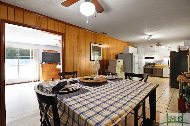 dining room featuring a ceiling fan and wood walls