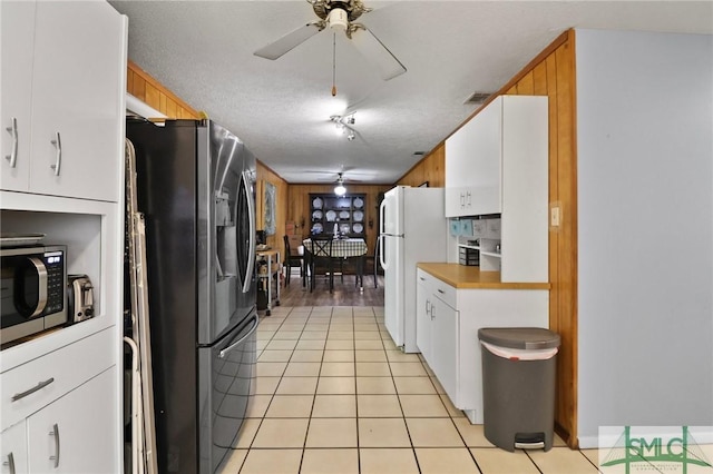 kitchen featuring white cabinets, light tile patterned flooring, ceiling fan, appliances with stainless steel finishes, and visible vents