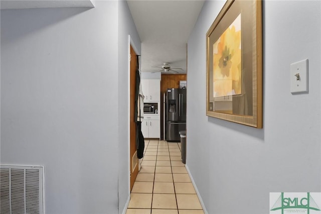 corridor with light tile patterned floors, baseboards, and visible vents