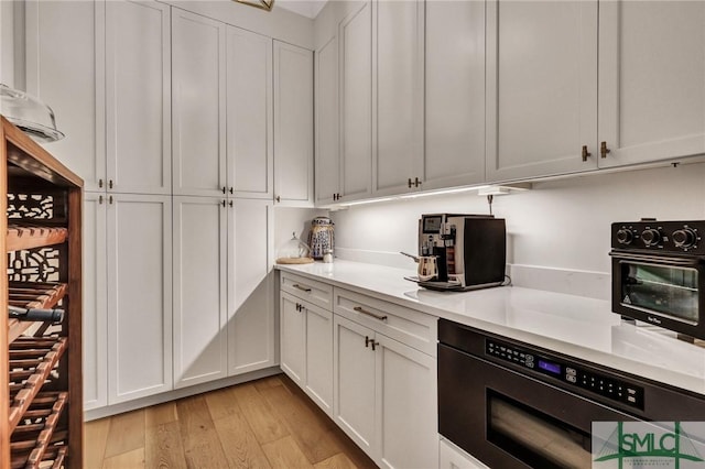 31 Tivoli Ln, Richmond Hill, GA 31324 - kitchen with white cabinets, light countertops, built in microwave, a toaster, and light wood-type flooring