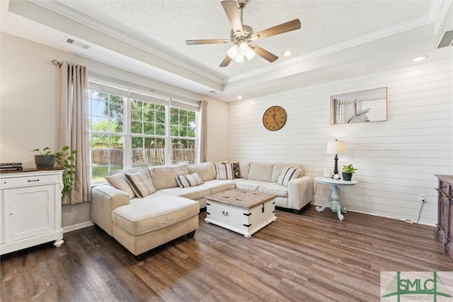 living area with dark wood-type flooring, visible vents, ceiling fan, and ornamental molding