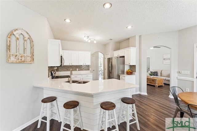 125 Blue Lake St, Richmond Hill, GA 31324 - kitchen with a peninsula, a sink, stainless steel appliances, a textured ceiling, and arched walkways
