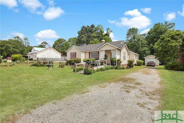 view of front of property with a front lawn, a garage, an outdoor structure, driveway, and a chimney