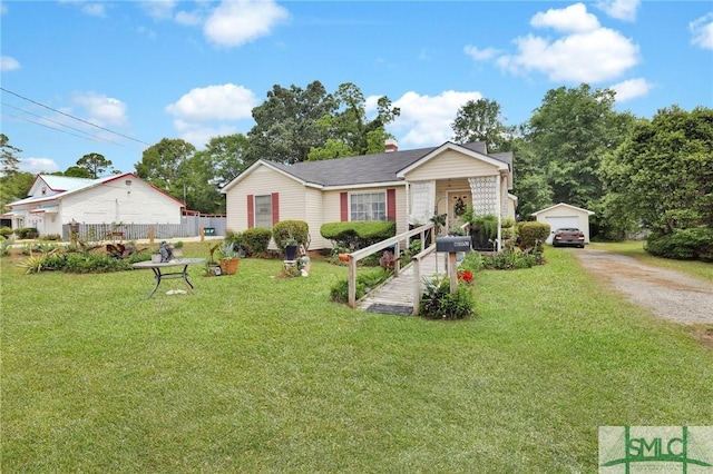 ranch-style home featuring a porch, a front yard, a garage, and an outbuilding